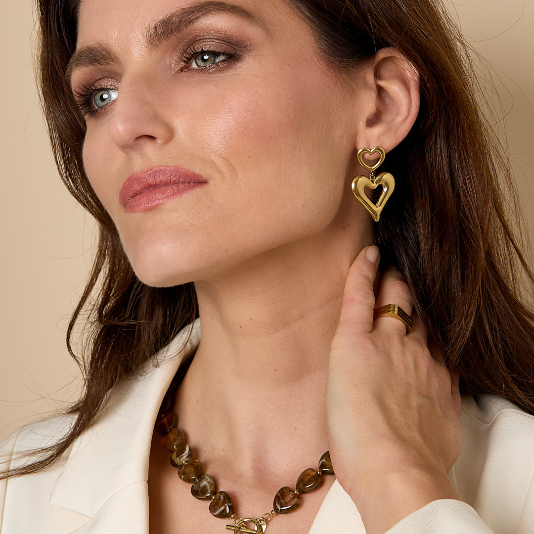 Gold heart drop earrings with a smaller heart above a larger heart.