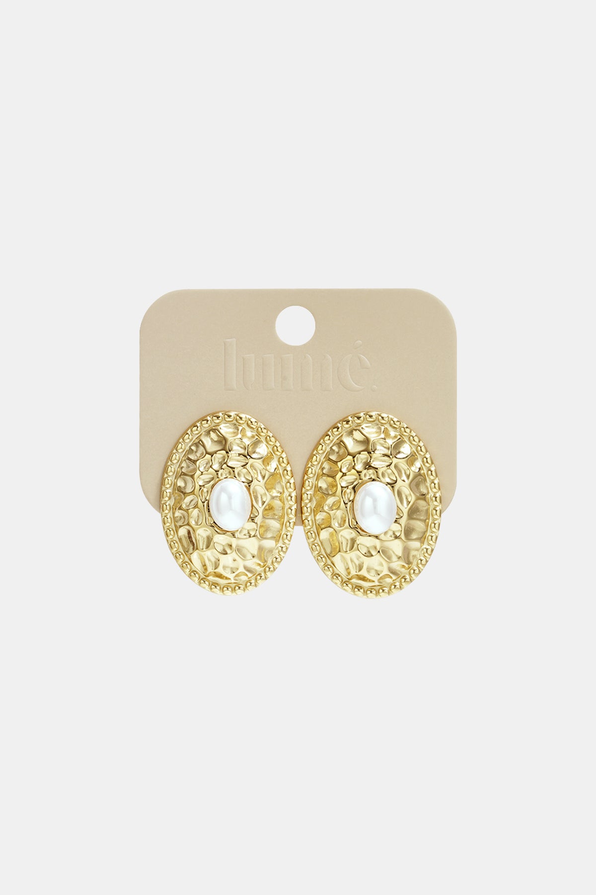 Gold oval stud earrings with a hammered texture and a pearl in the center, on a light beige card.