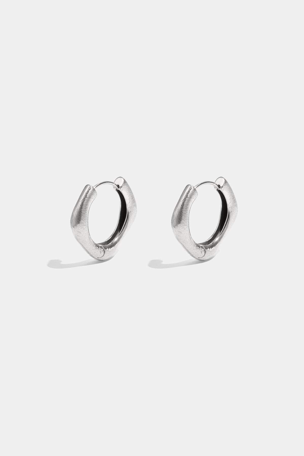 A pair of silver Astra hoop earrings with a unique square shape and rounded edges.