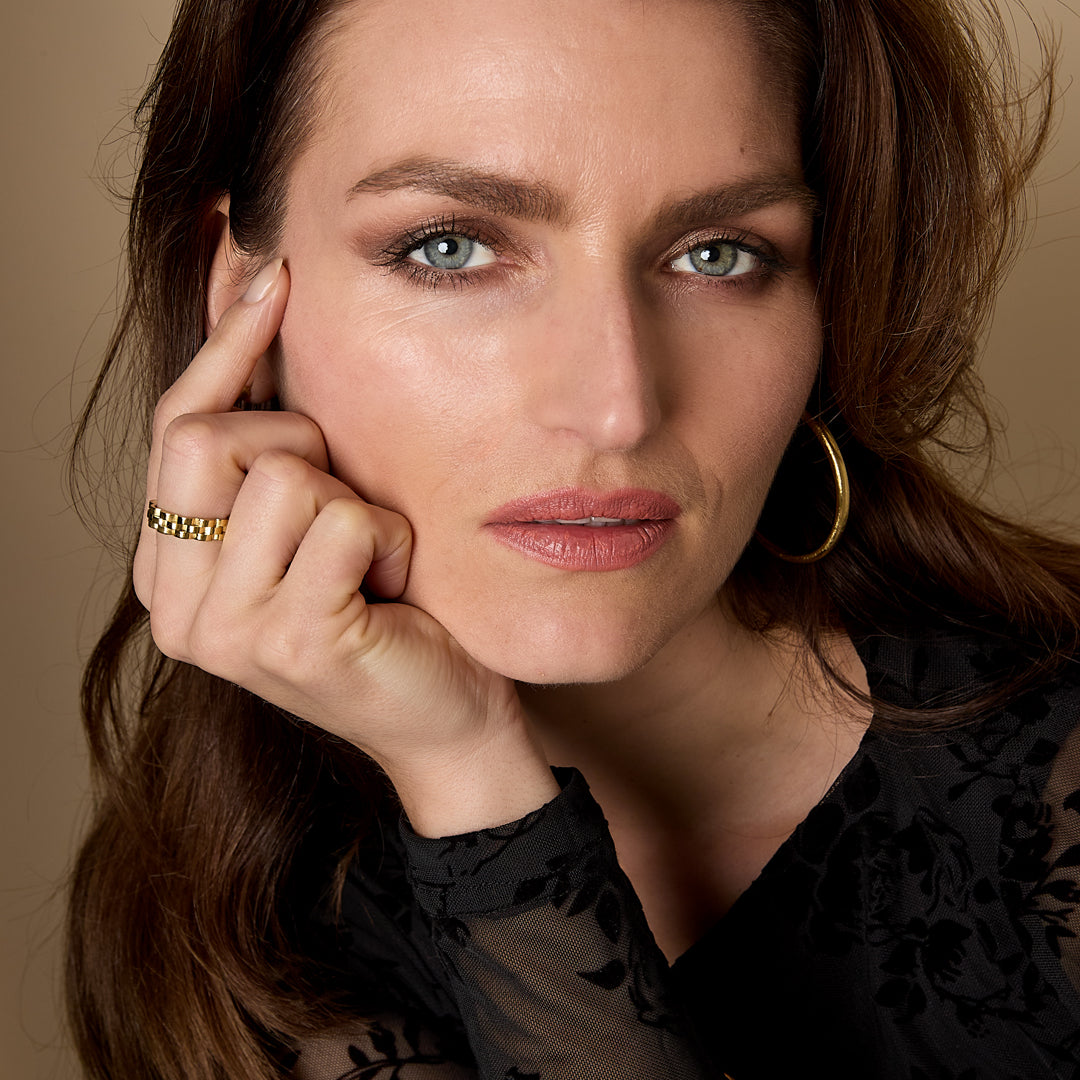 Woman wearing the Elara Bangle Bracelet, a thin gold band on her wrist.