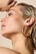 Gold hoop earrings worn by a woman, showing the detail of the jewelry.