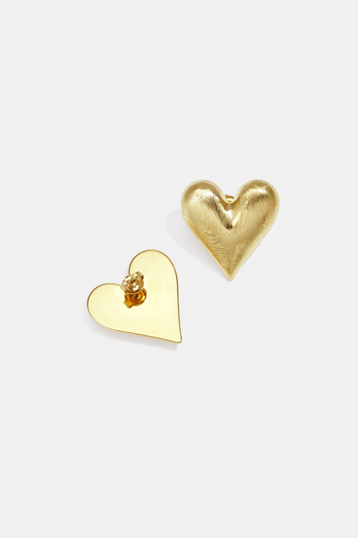 Gold heart stud earrings, one with a brushed finish, the other flat and smooth.