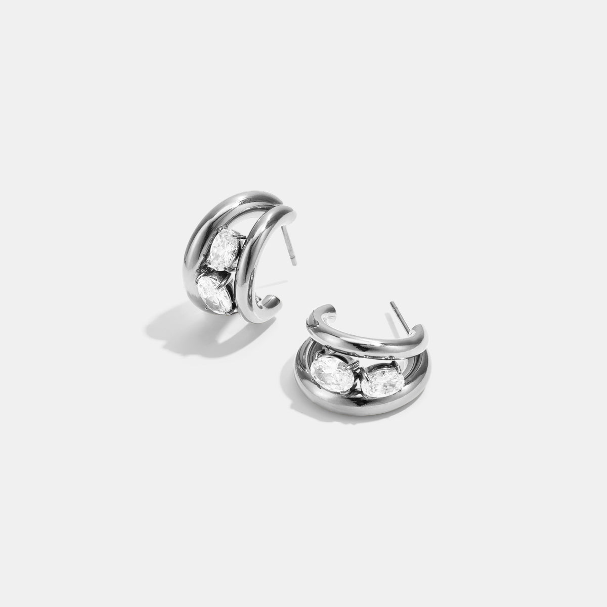 Silver hoop earrings with three clear oval stones on each earring.