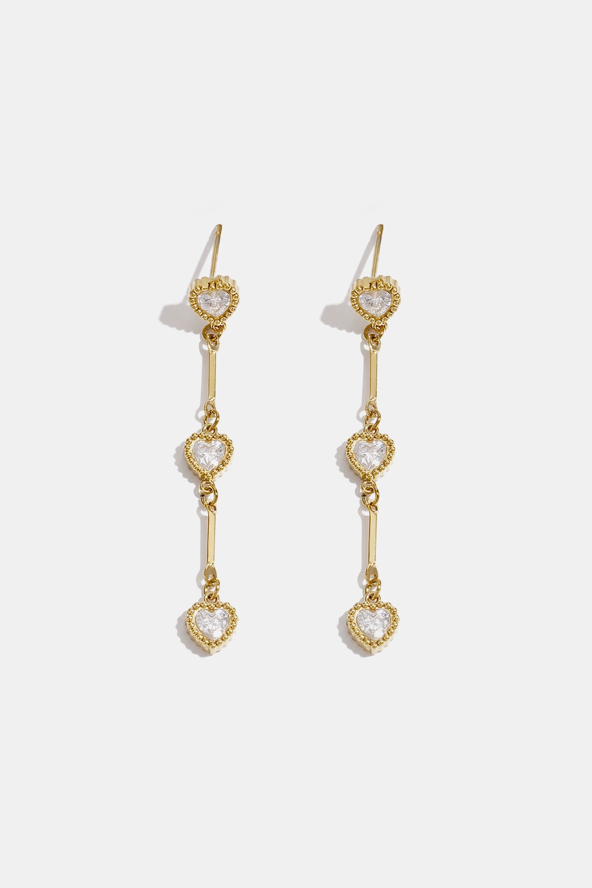 Gold dangle earrings with three heart-shaped zircon charms hanging from a bar.