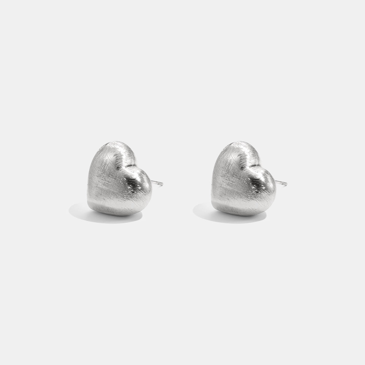 Two silver heart-shaped stud earrings with a matte finish, displayed against a white background.