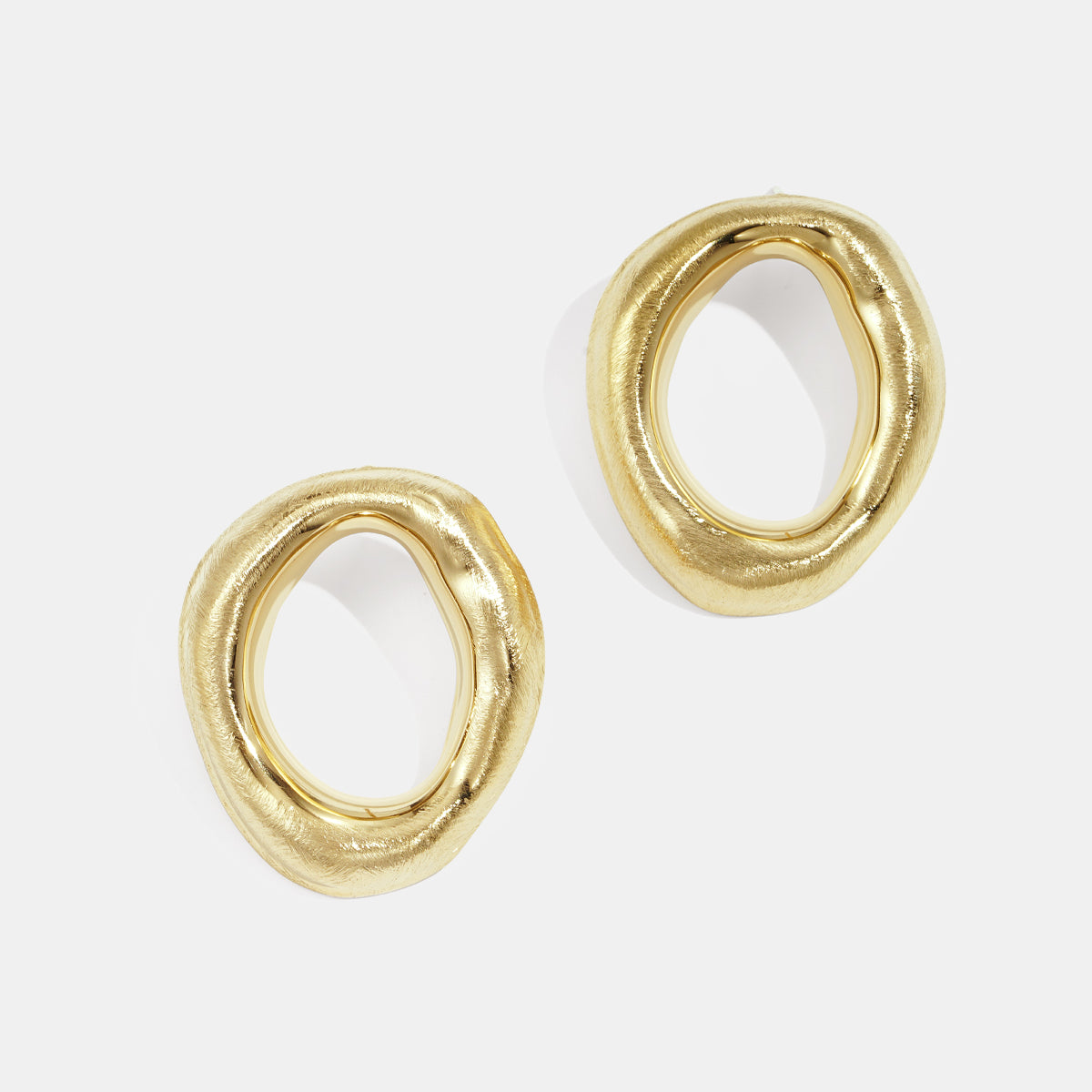 Two gold-toned, irregular-shaped stud earrings with a brushed finish.