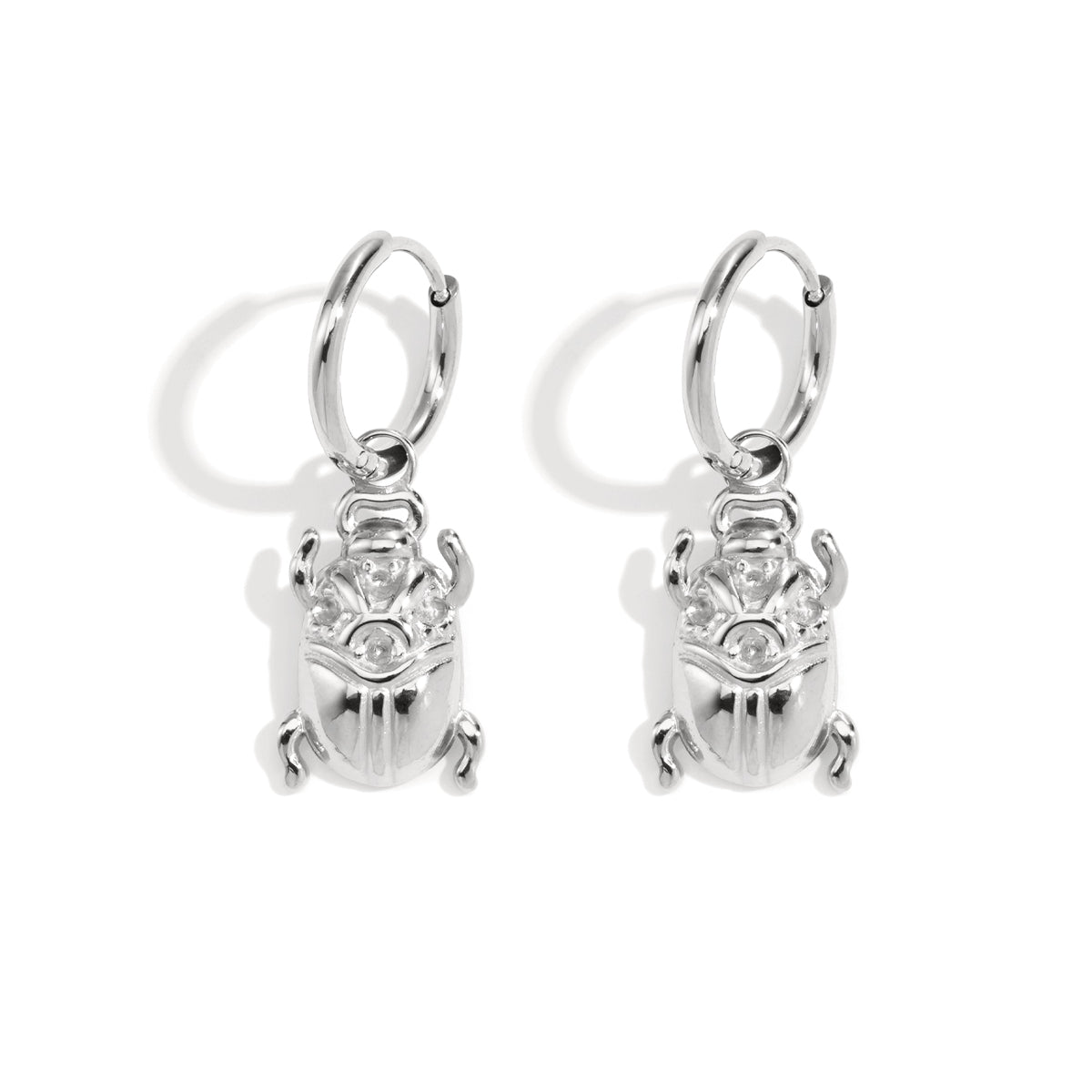 Silver hoop earrings with dangling scarab beetle charms.