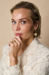 Gold heart drop earrings with rhinestones and a diamond ring on a woman's hand.