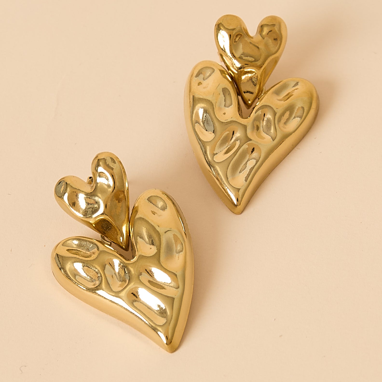 Gold stacked heart stud earrings with textured surface.