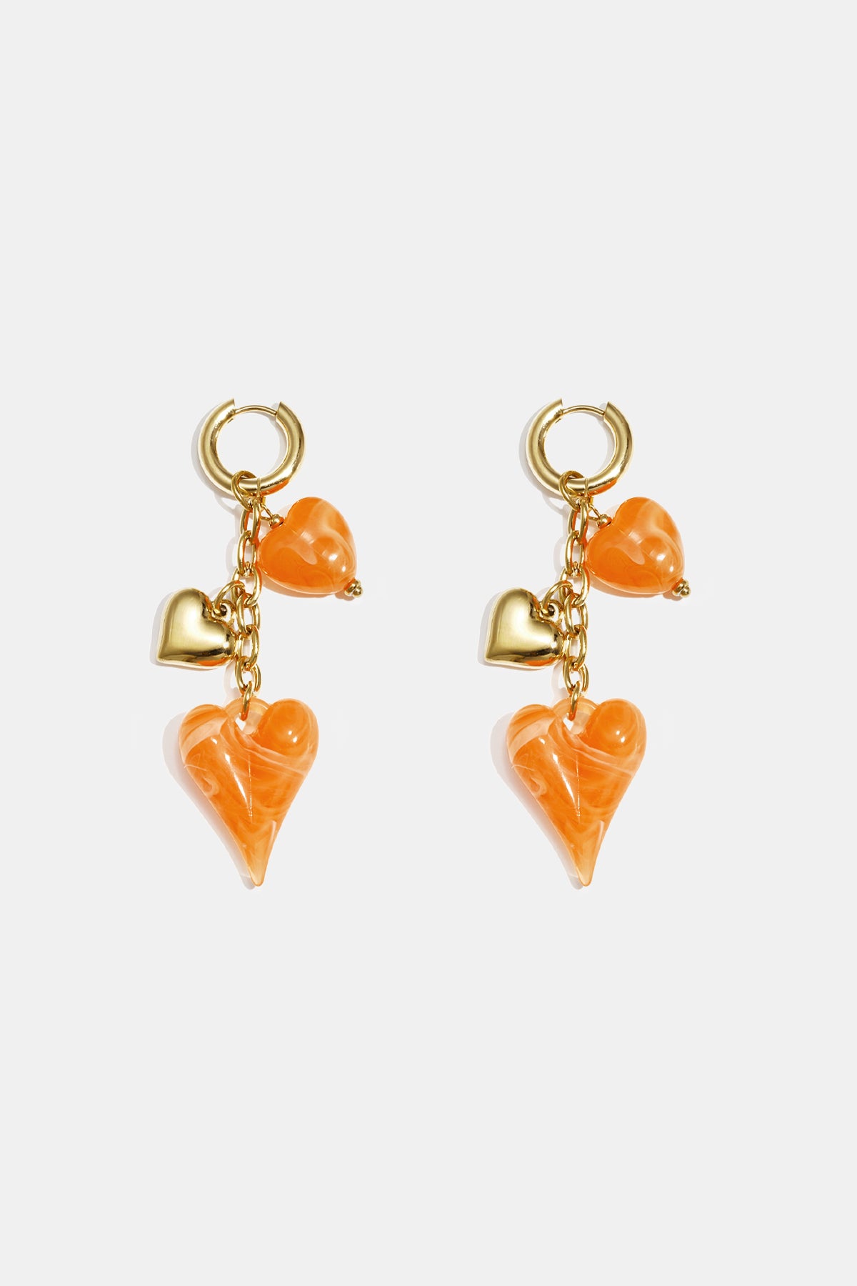 Gold hoop earrings with dangling orange acrylic hearts and gold heart charms.