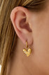 Gold heart-shaped drop earrings with rhinestones on a woman's ear.