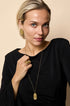 Gold irregular charm long necklace on a woman wearing a black dress.