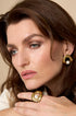 Gold circle stud earrings with a pearl accent, worn by a woman.