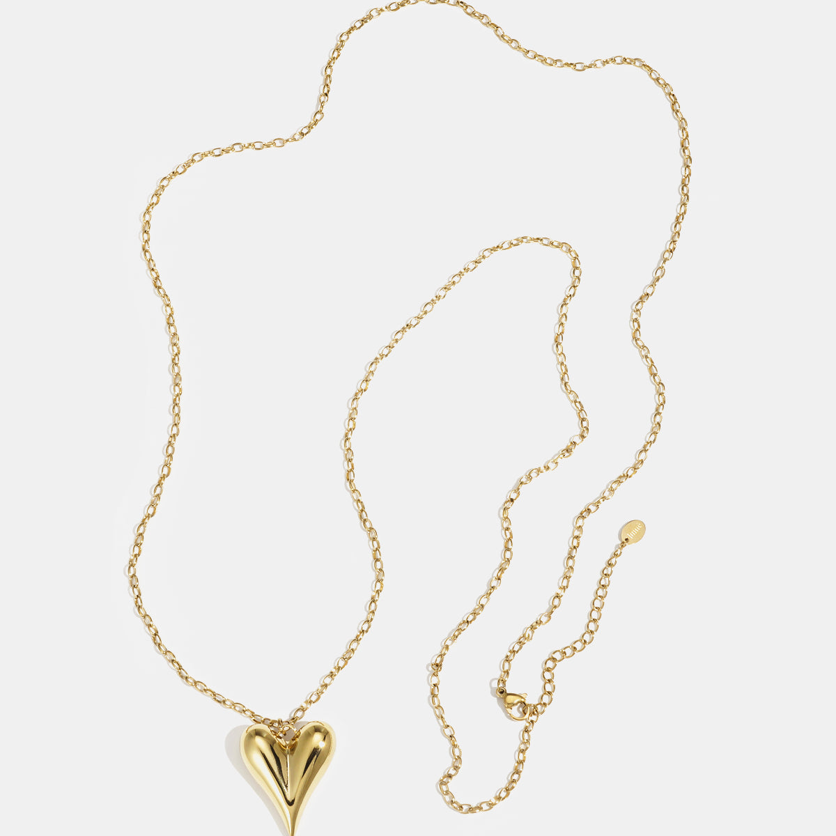 Gold heart pendant necklace with a long chain and clasp closure.