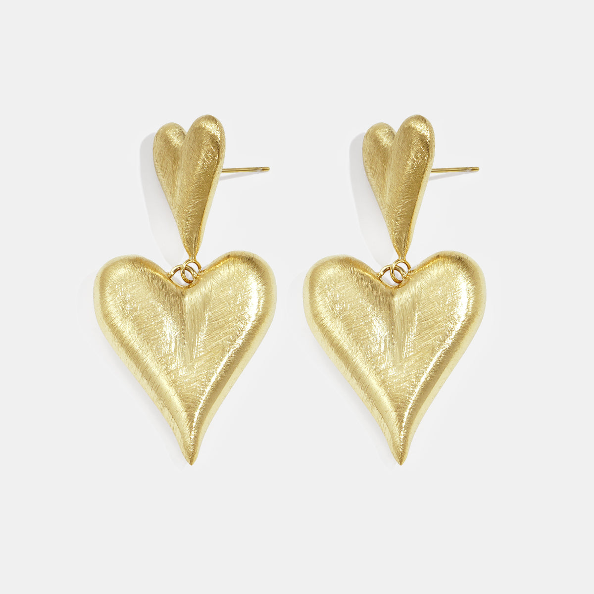 Gold heart drop earrings with a smaller heart stud and a larger dangling heart.