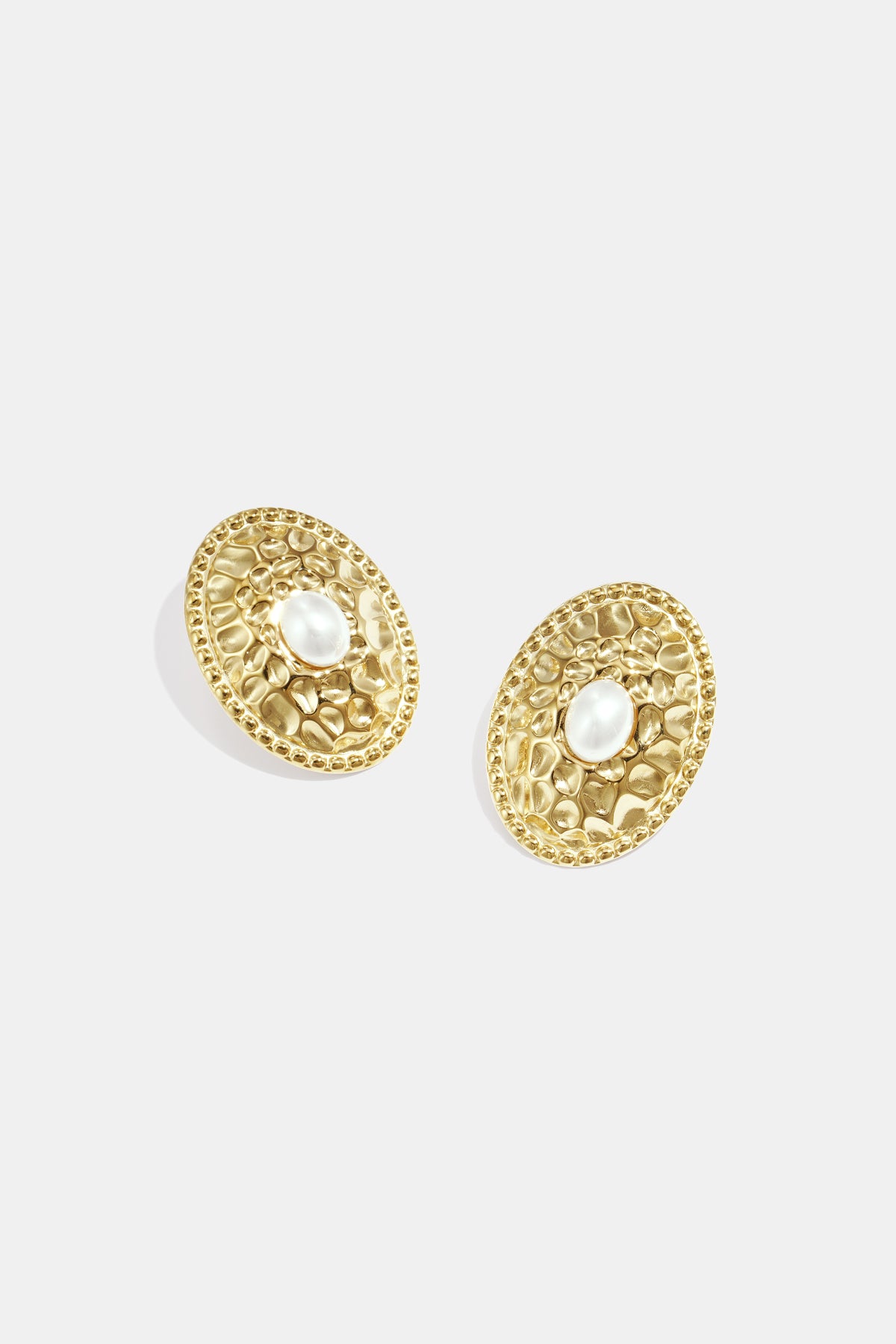 Gold oval stud earrings with a hammered texture and a pearl in the center.
