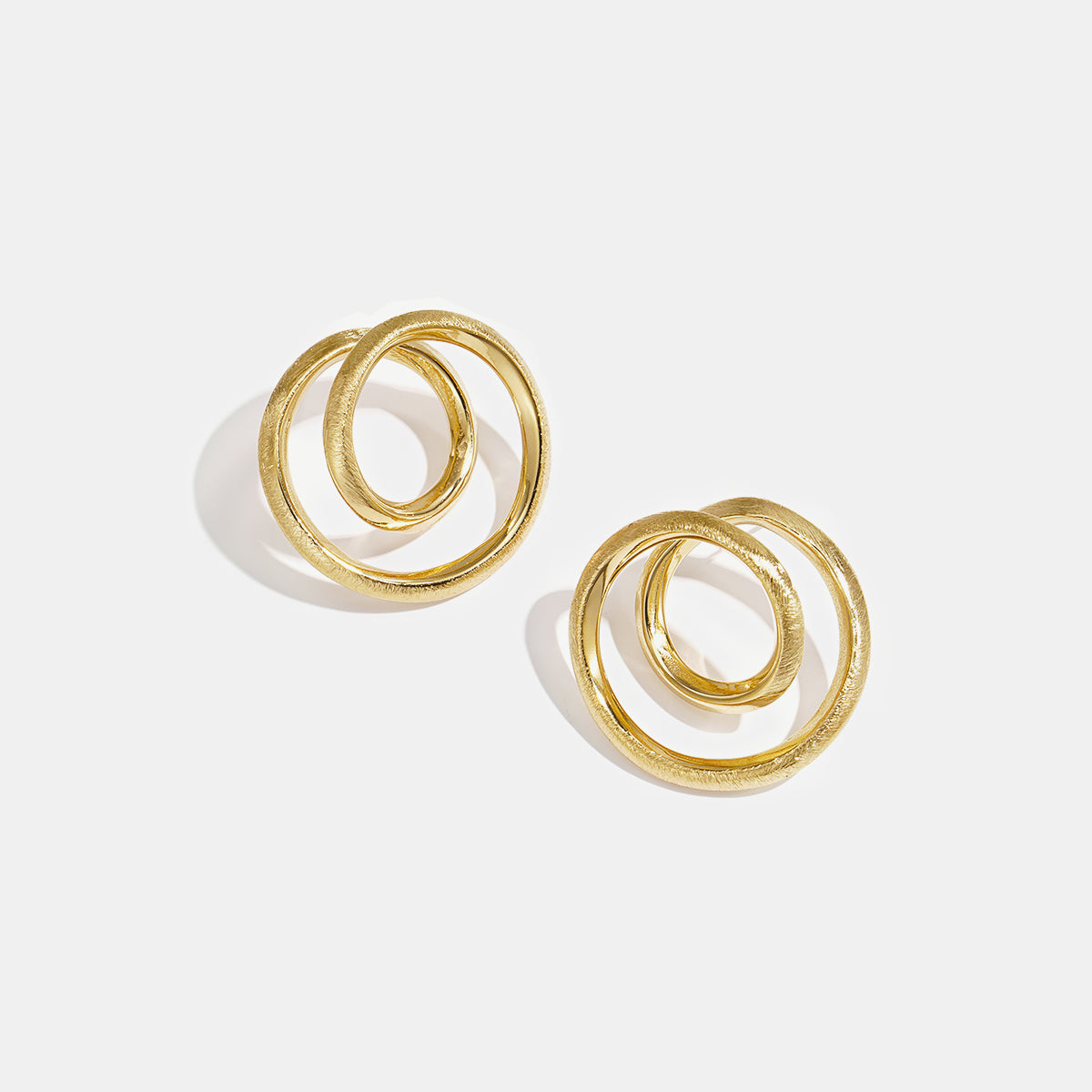 Two gold spiral circle stud earrings on a white background.
