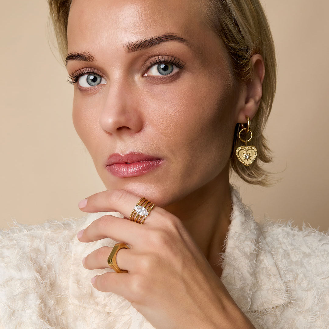 Gold-tone adjustable ring with a central marquise-cut zircon stone, worn on a woman's finger.