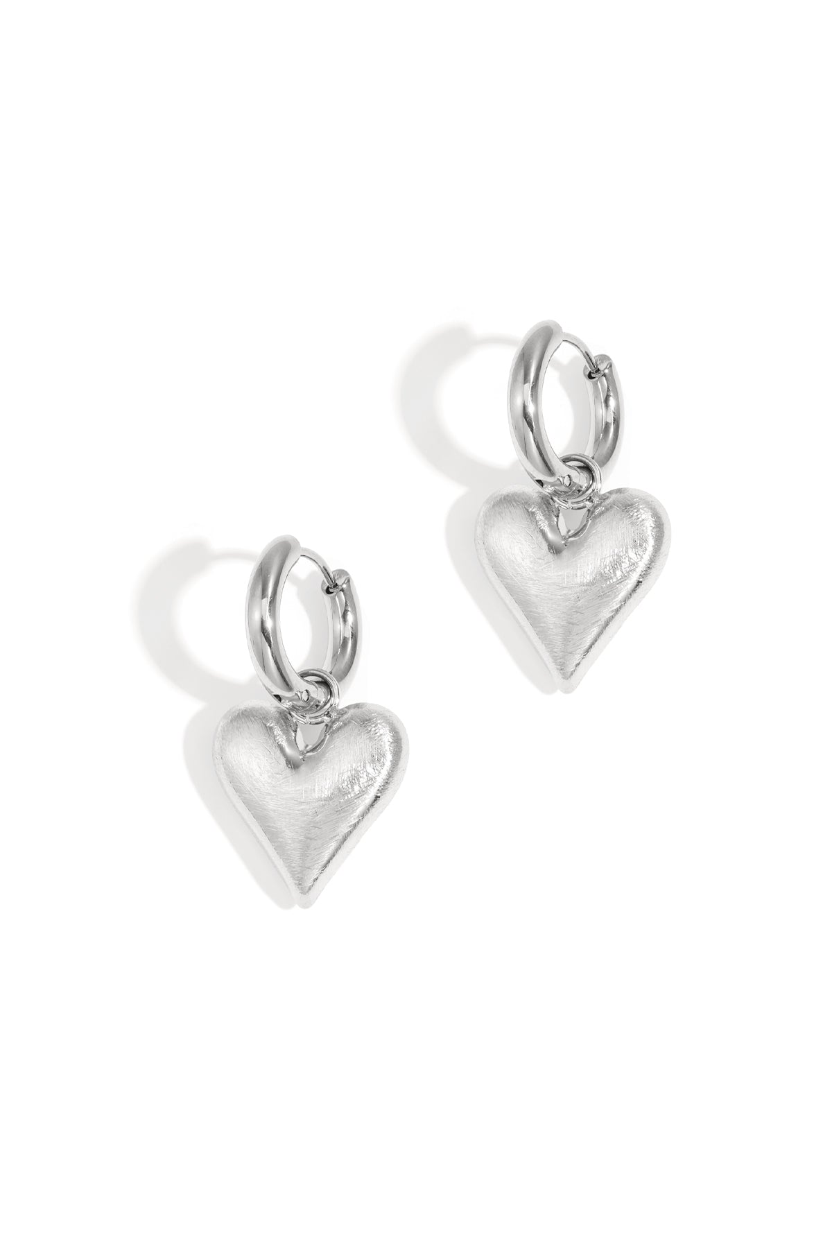 Silver heart drop earrings with hoop clasps on a white background.