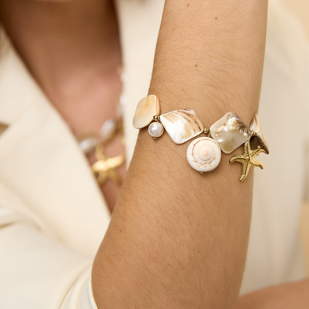 Ocean Charm Bracelet with shells, pearls, and starfish charms on a woman's arm.