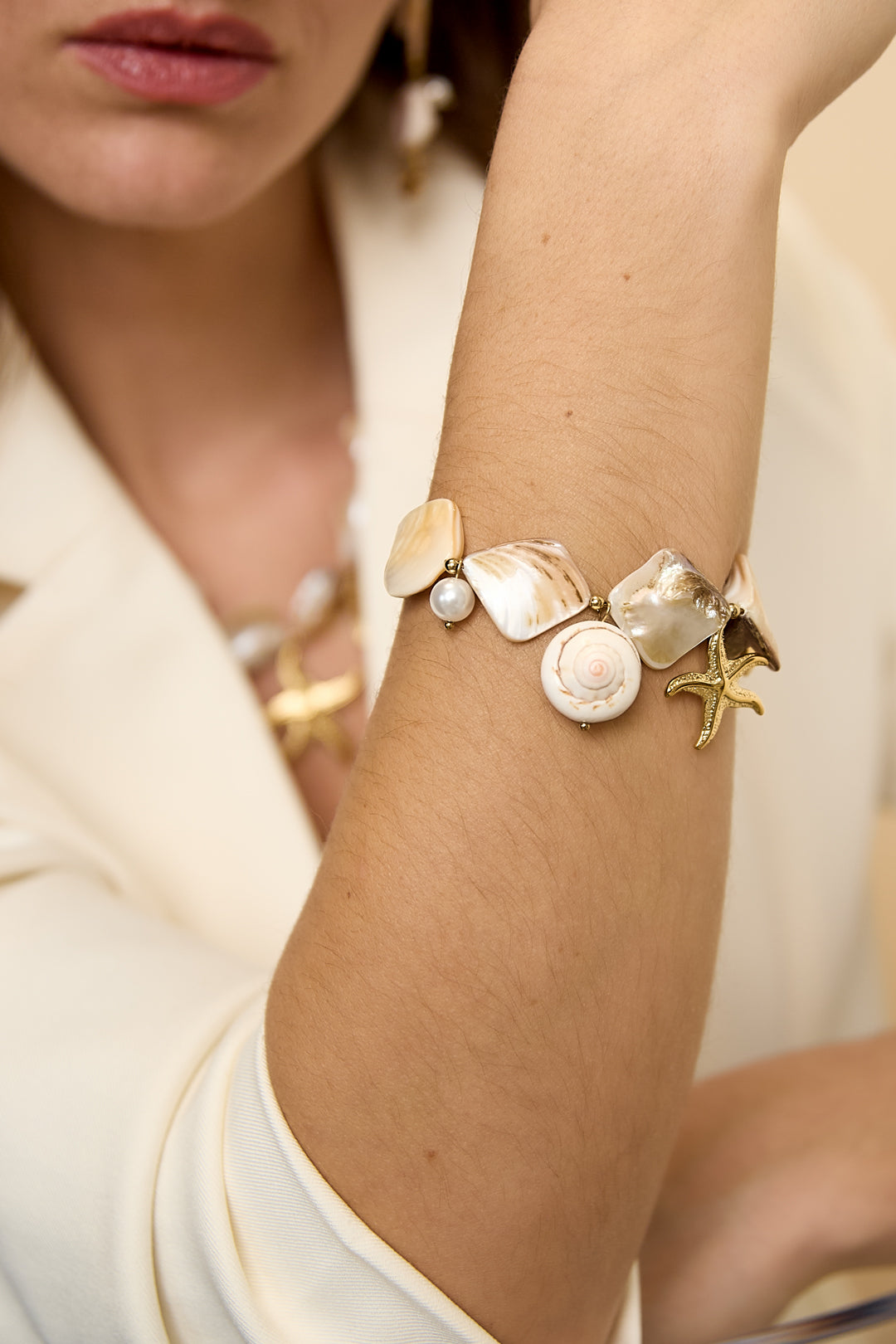 Ocean Charm Bracelet with shells, pearls, and starfish charms on a woman's arm.