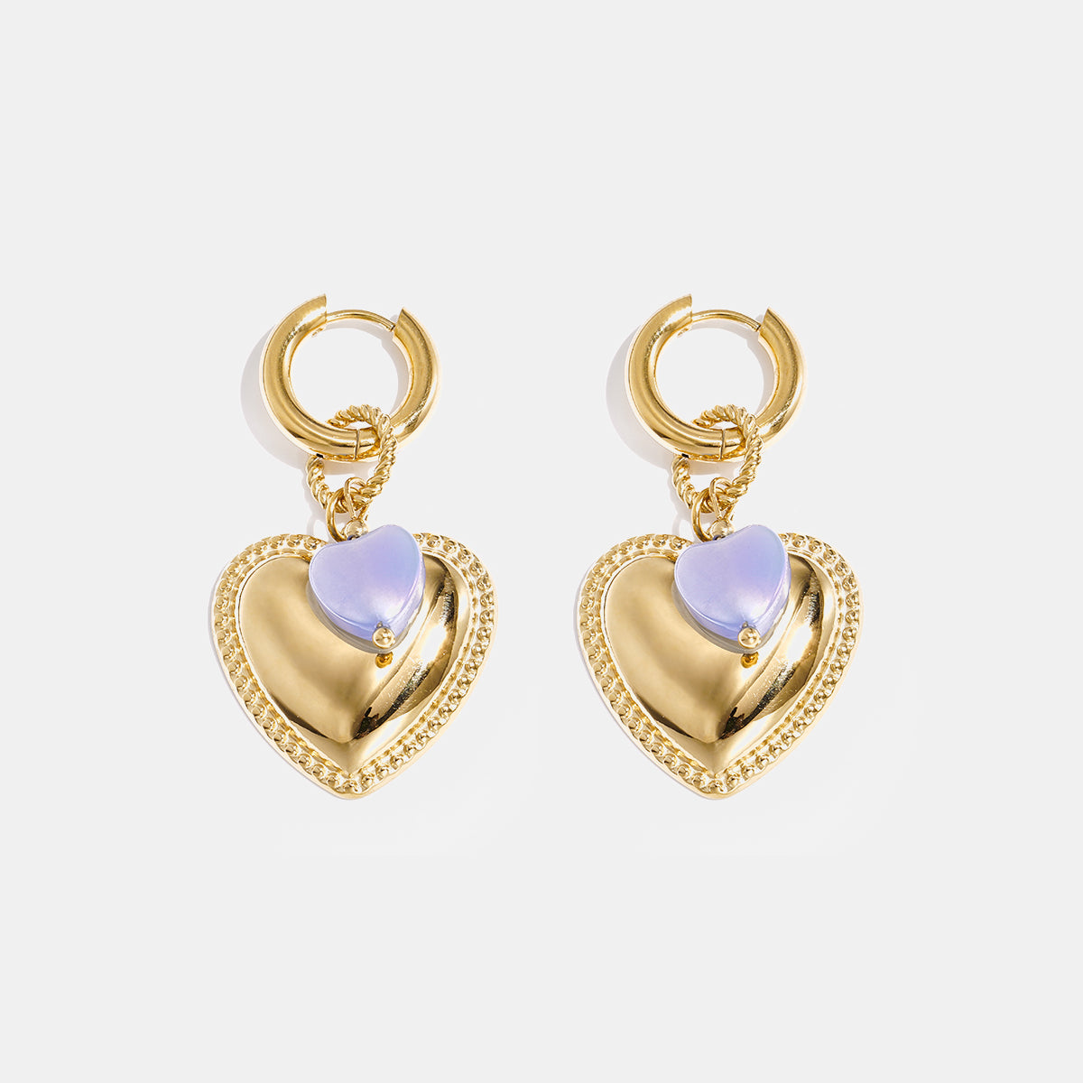 Gold hoop earrings with a large gold heart pendant and a small blue heart bead.