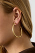 Gold hoop earrings with a brushed finish on a woman's ear.