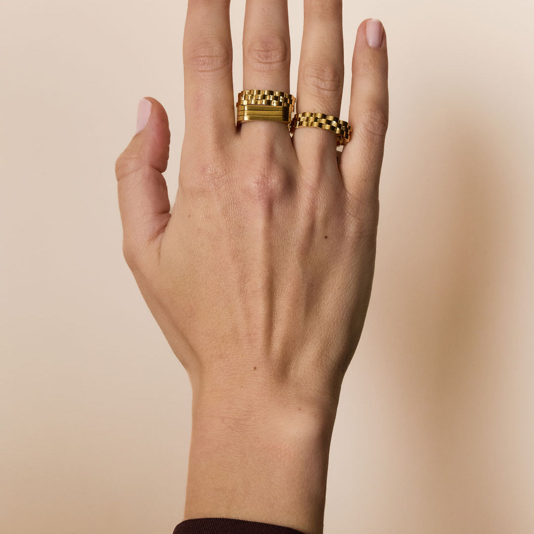 Gold-colored irregular minimalist ring on a hand.