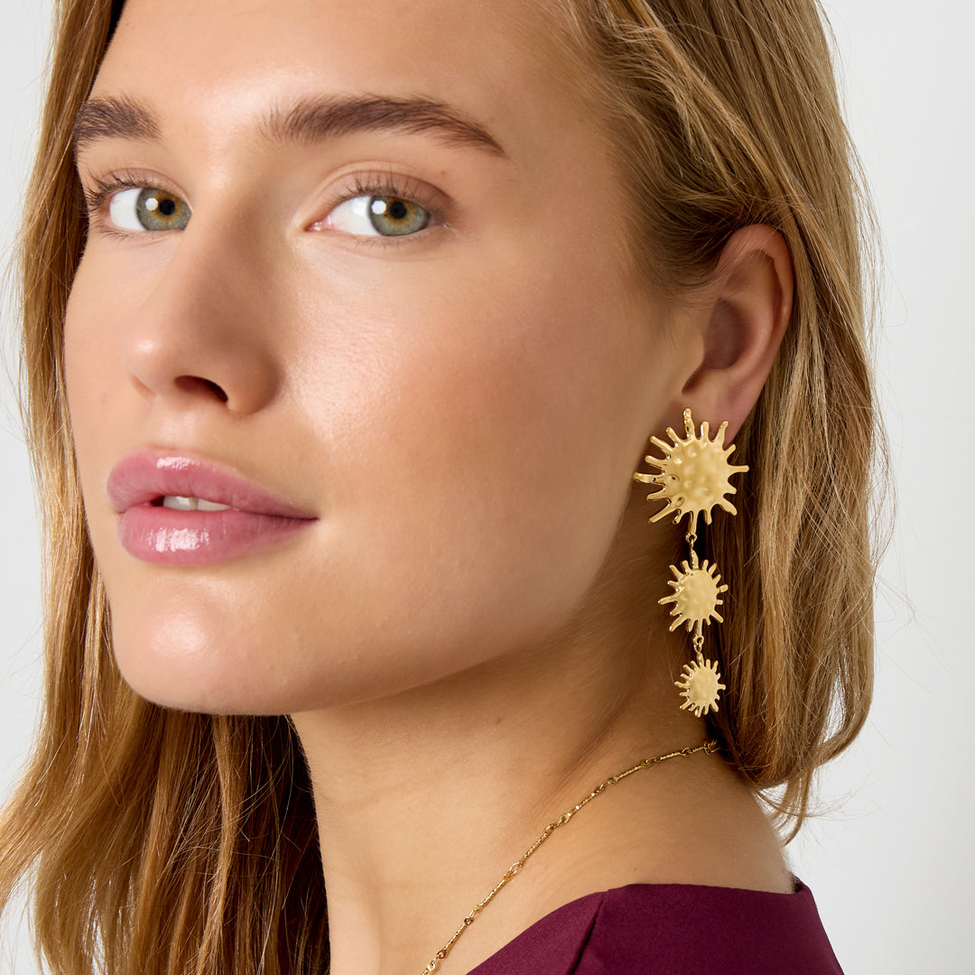 Gold-tone dangle earrings with three sun motifs of decreasing size.