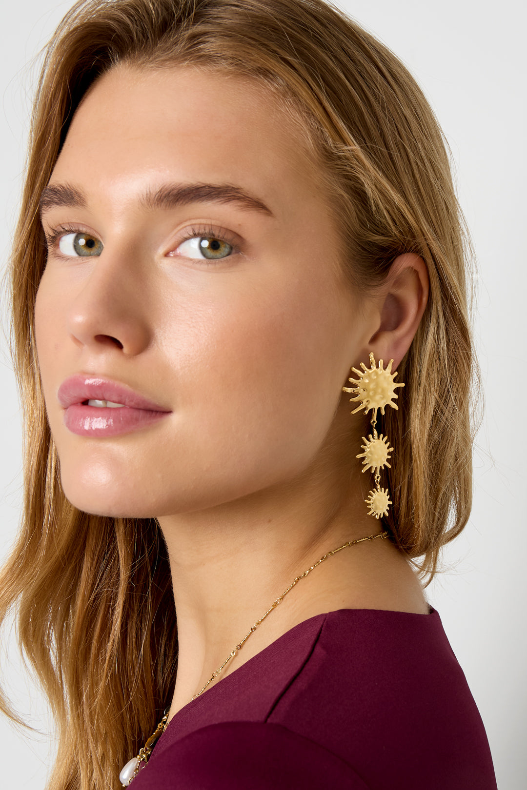 Gold-tone dangle earrings with three sun motifs of decreasing size.