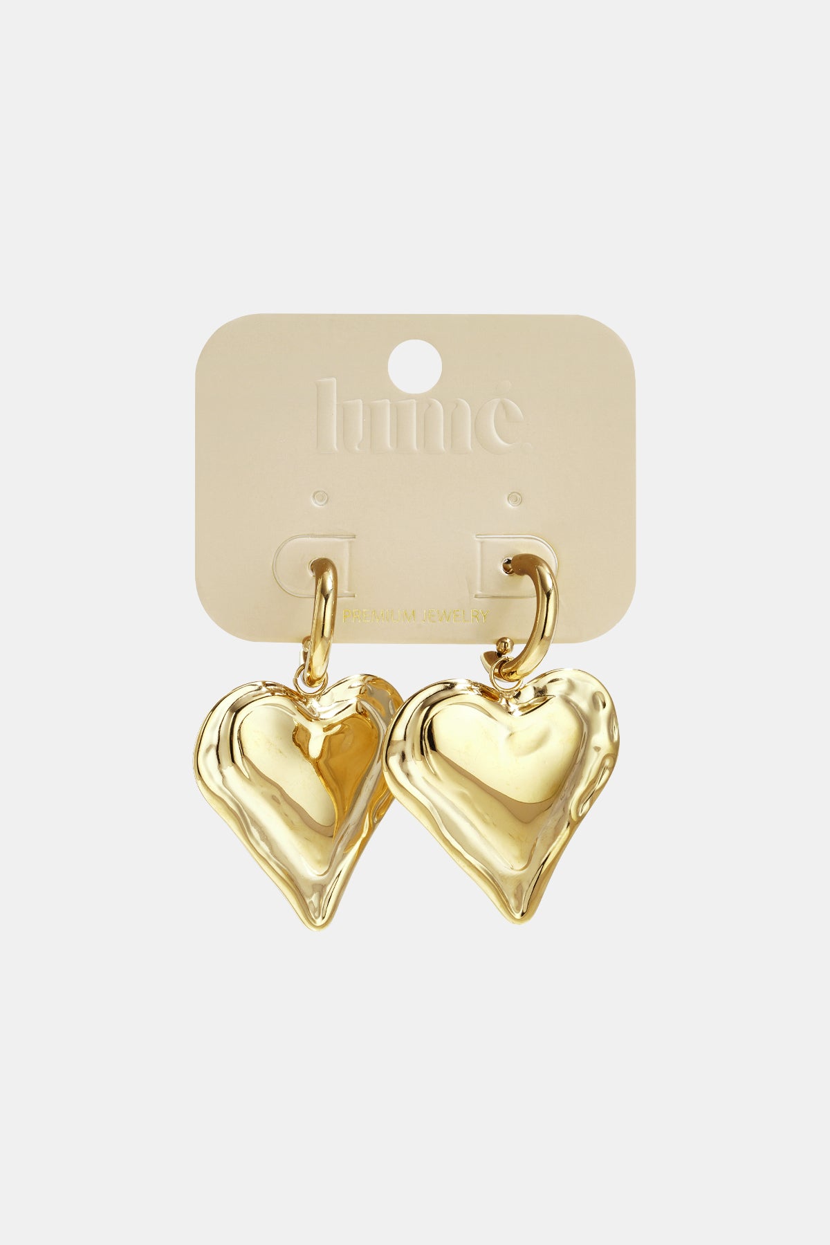 Gold heart drop earrings on a light beige card with "hume PREMIUM JEWELRY" printed on it.