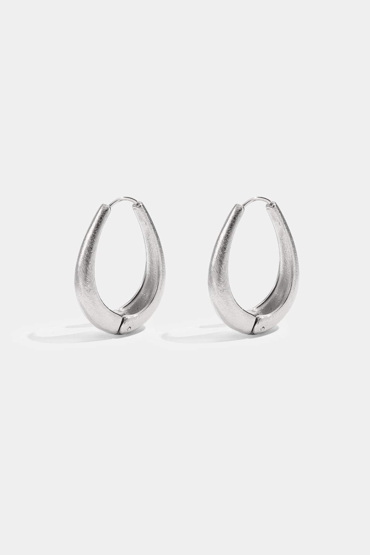 A pair of silver irregular oval hoop earrings with a brushed finish.