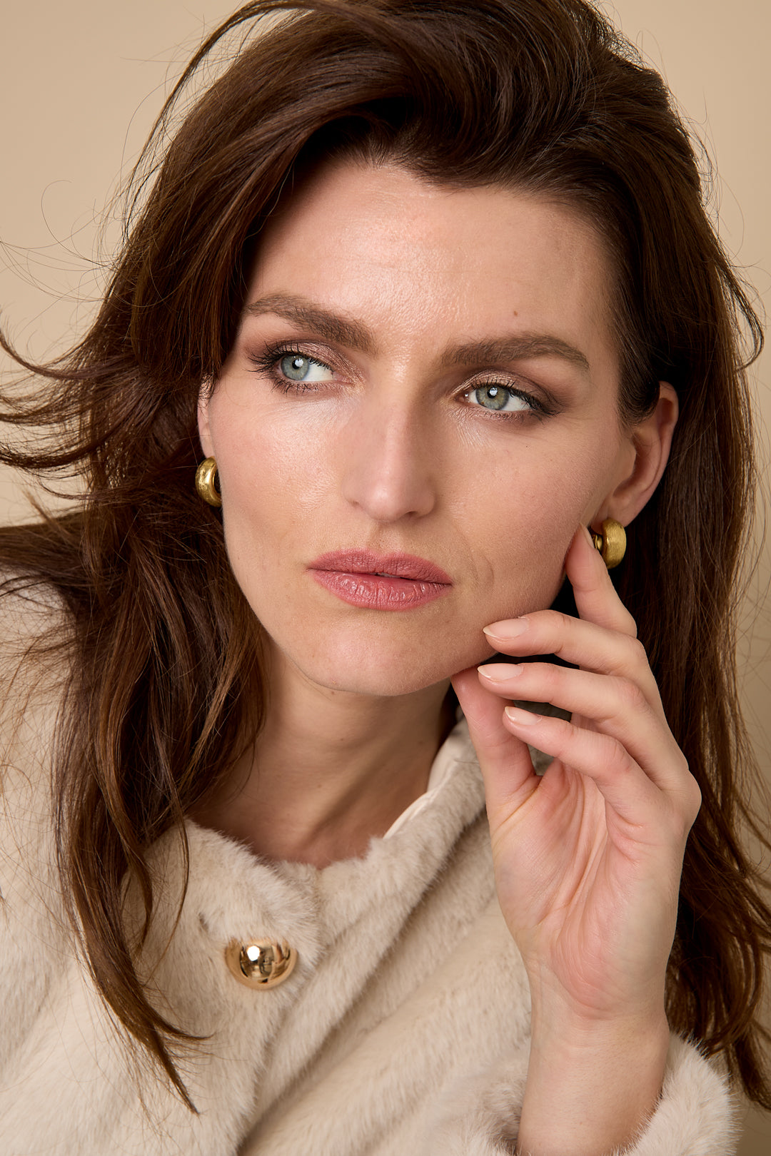 Elysian Hoop Earrings in gold, worn by a model with brown hair and light blue eyes.