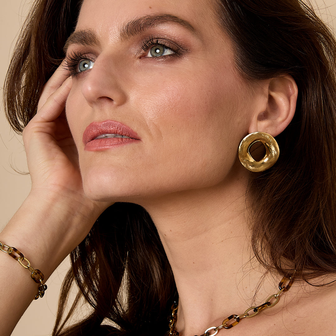 Gold circular Aura statement earrings with a textured finish.