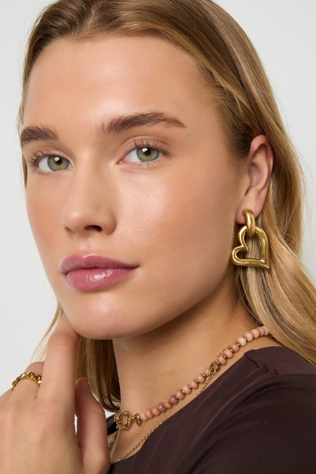 Gold heart drop earrings with a textured finish, worn by a model.