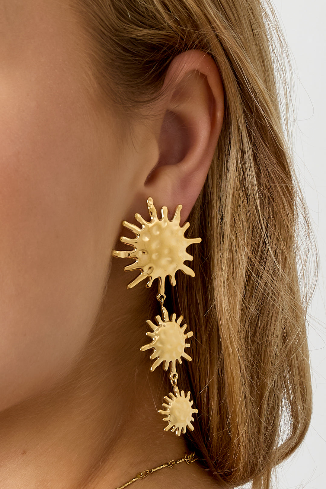 Gold dangle earrings with three sunburst charms of decreasing size.
