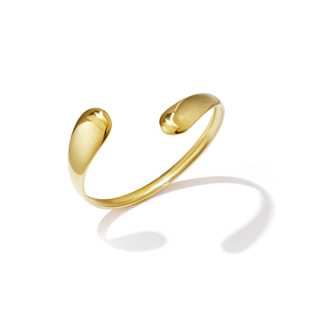Gold irregular cuff bracelet with a polished finish, casting a shadow on a white background.