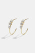 Gold hoop earrings with three clear stones each, on a white background.