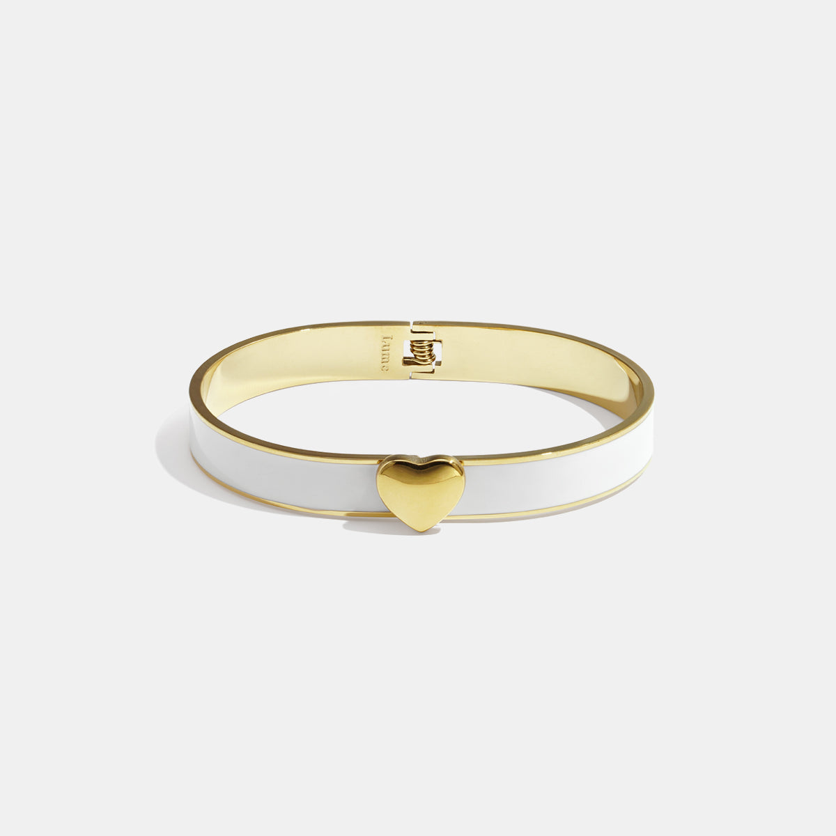 Gold-tone bangle with white enamel and a gold heart charm.