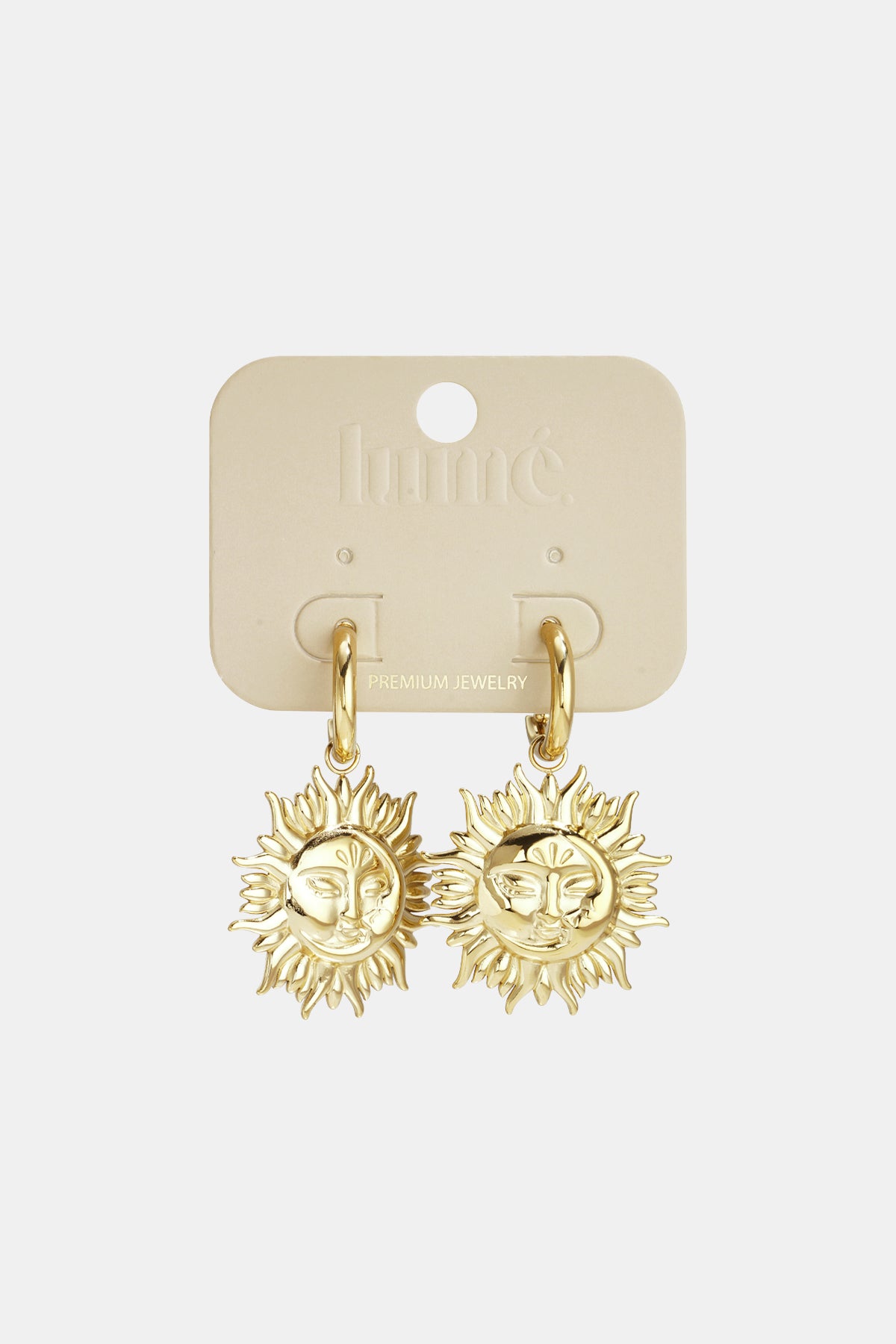 Gold-tone hoop earrings with dangling sun face charms, displayed on a cream-colored card.