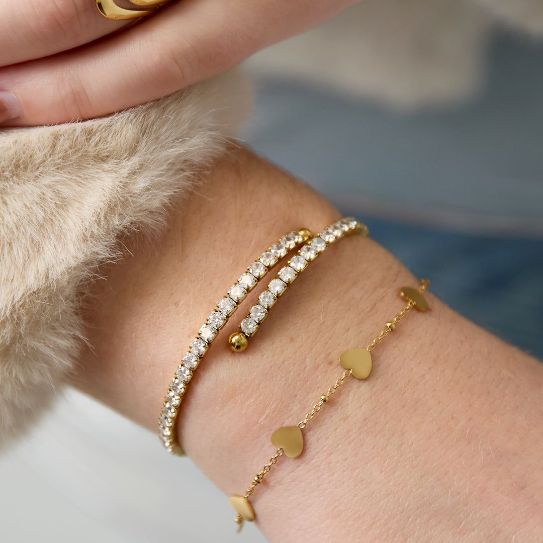 Gold cuff bracelet with rhinestones and a heart charm bracelet.