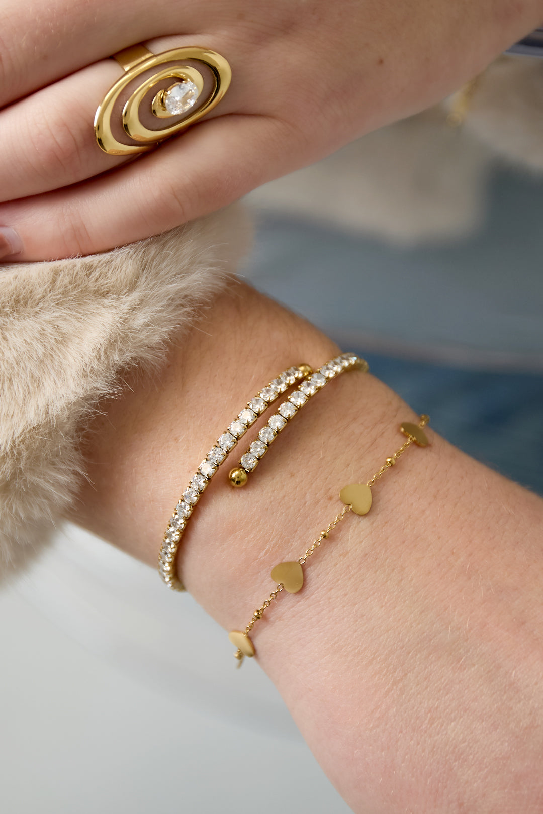 Gold cuff bracelet with rhinestones and a heart charm bracelet.