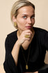 Gold irregular spiral ring on a woman's finger, with matching earrings and necklace.