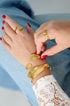 Gold irregular cuff bracelet on a woman's wrist, paired with a matching ring.