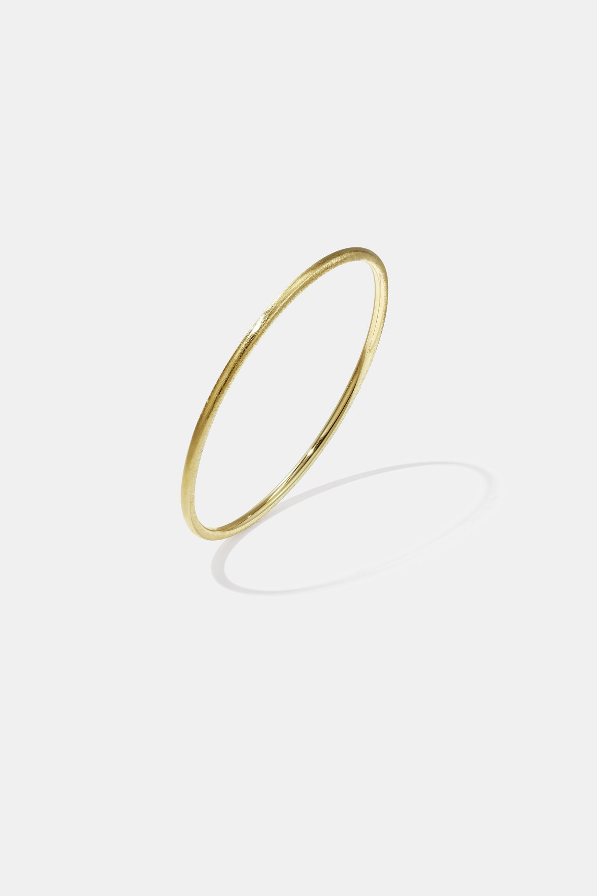 Gold-toned 3 mm wide brushed finish bangle bracelet with a subtle texture.