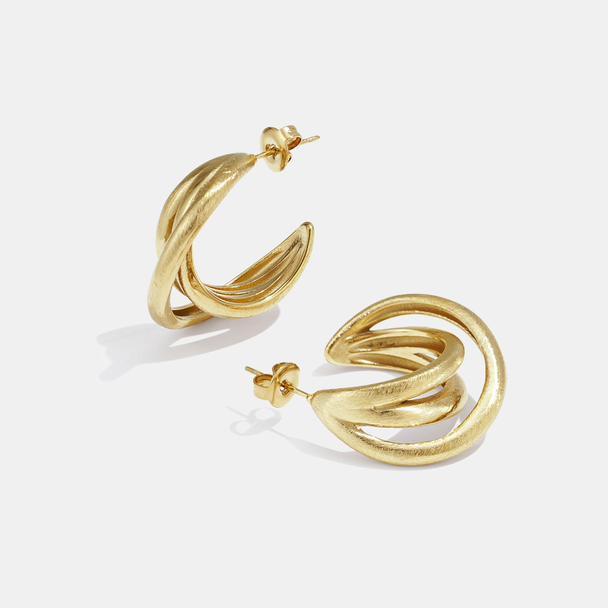 Gold Astra hoop earrings with a twisted, layered design.