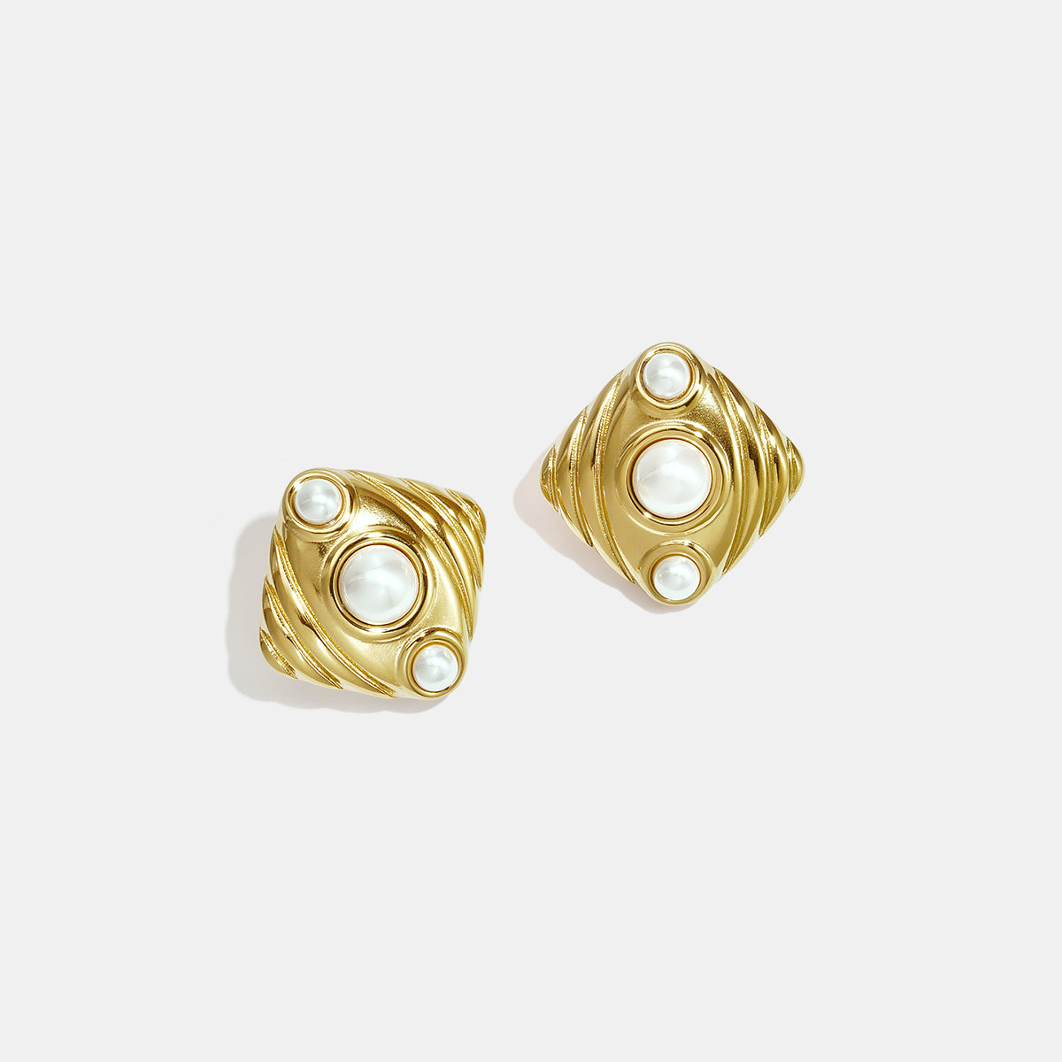 Gold Aurelia stud earrings with pearl accents and a textured geometric design.