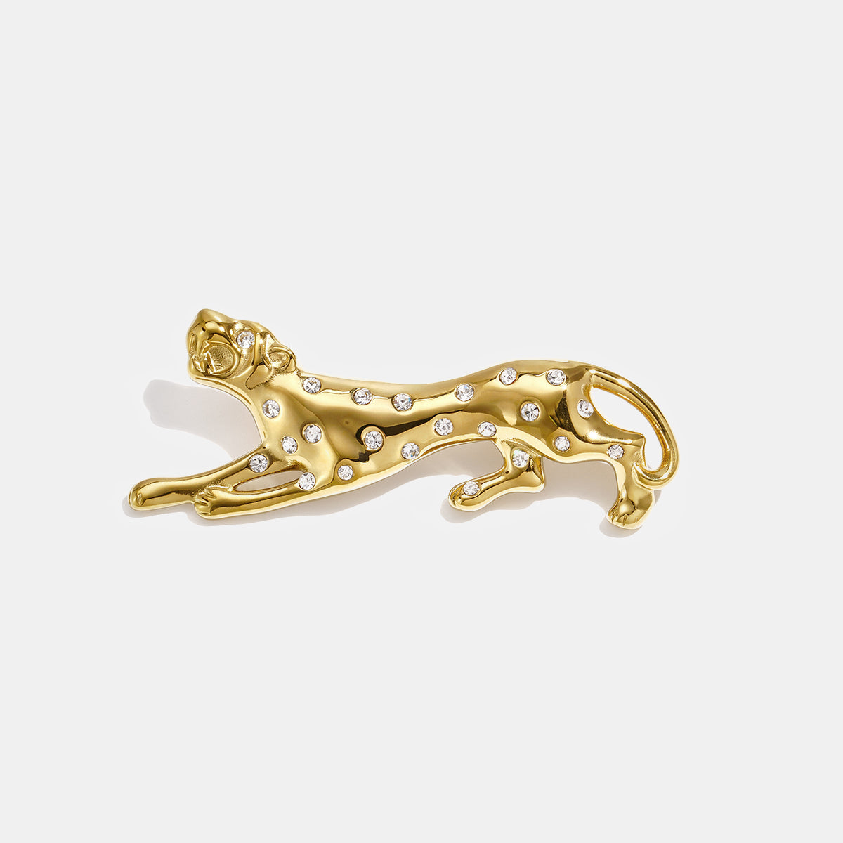 Gold-colored cheetah brooch with clear rhinestones, lying down.