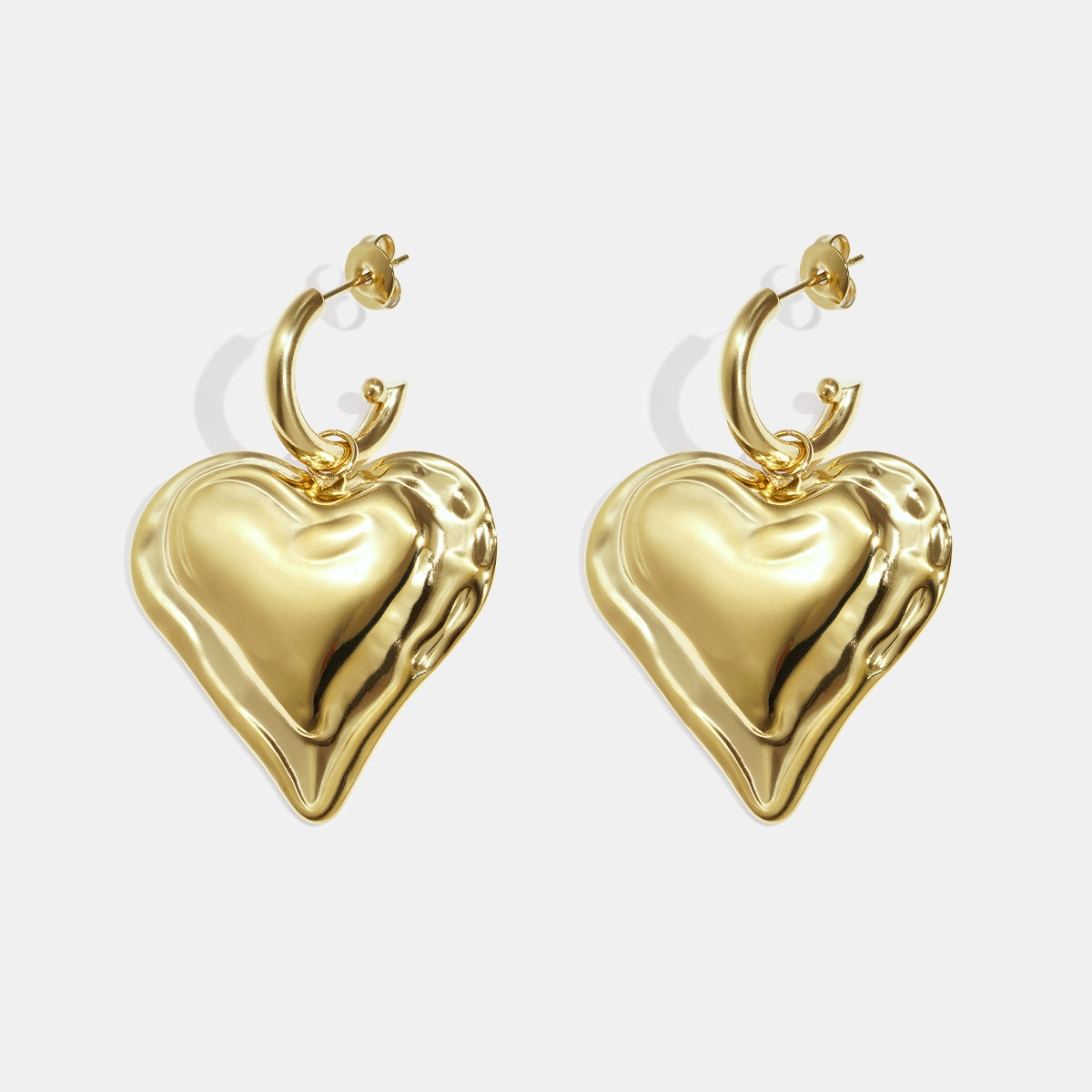 Gold heart drop earrings with a textured surface, attached to a hoop.